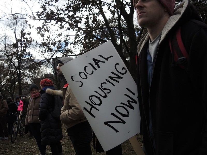 A person holds a sign that says "Social Housing Now."